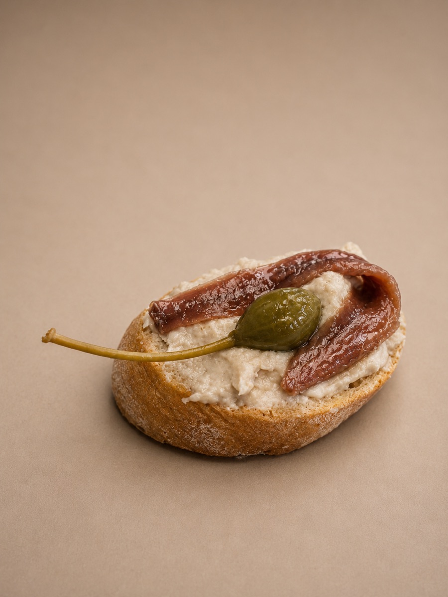 Un cicchetto: crostino con crema di tonno, fiore di cappero e acciuga