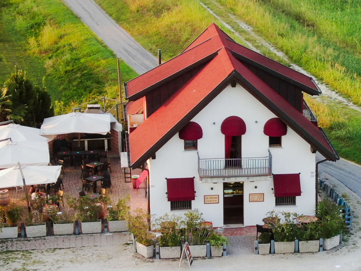 La facciata dell'osteria con le tende rosse alle finestre, verso sera